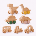 Wooden toy vehicles for toddlers, including dinosaurs, a bus, a tractor, and cars, crafted from natural light wood with colorful painted wheels on a white background.